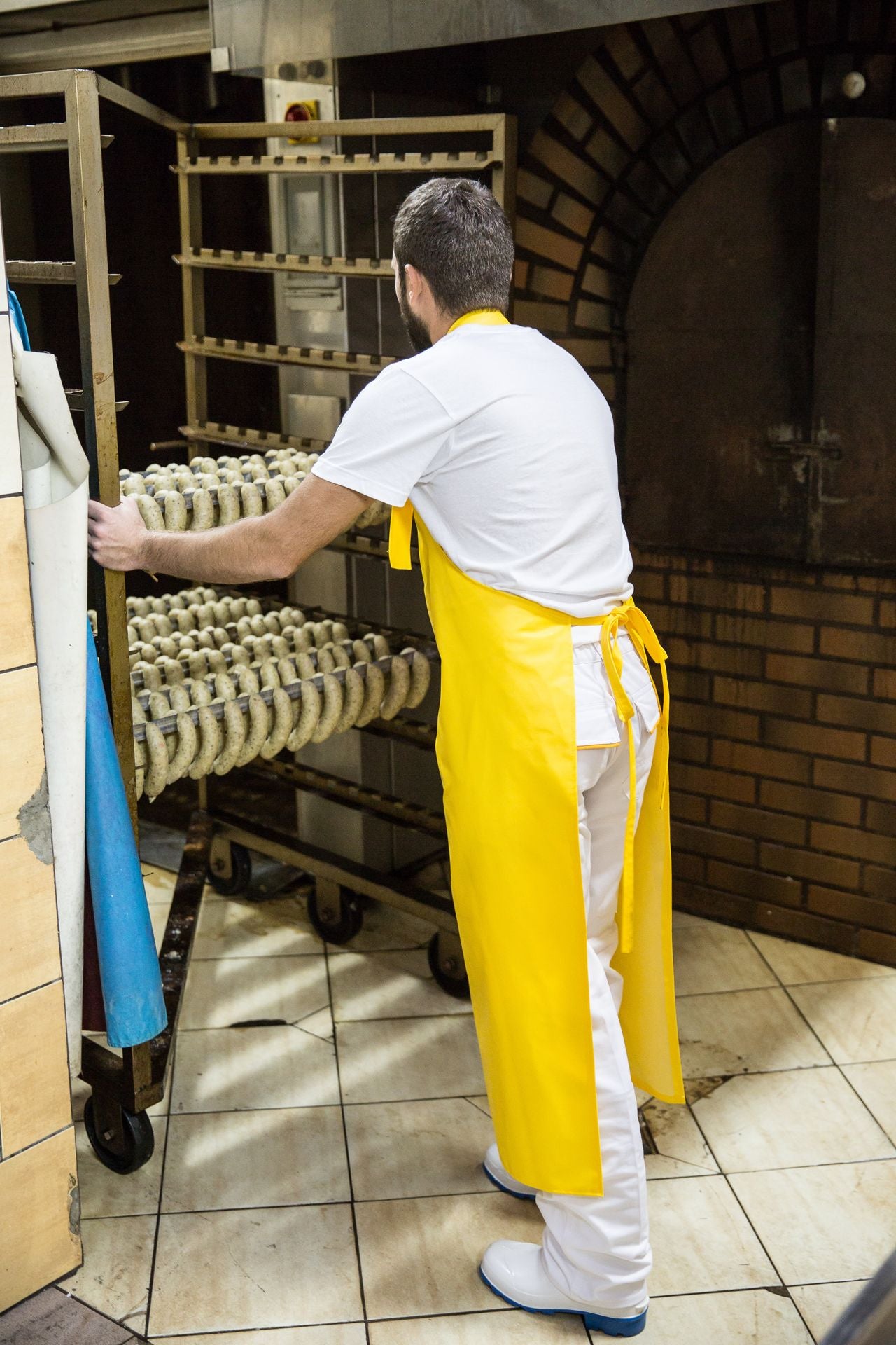 Person in a yellow work apron working  in a kitchen setting